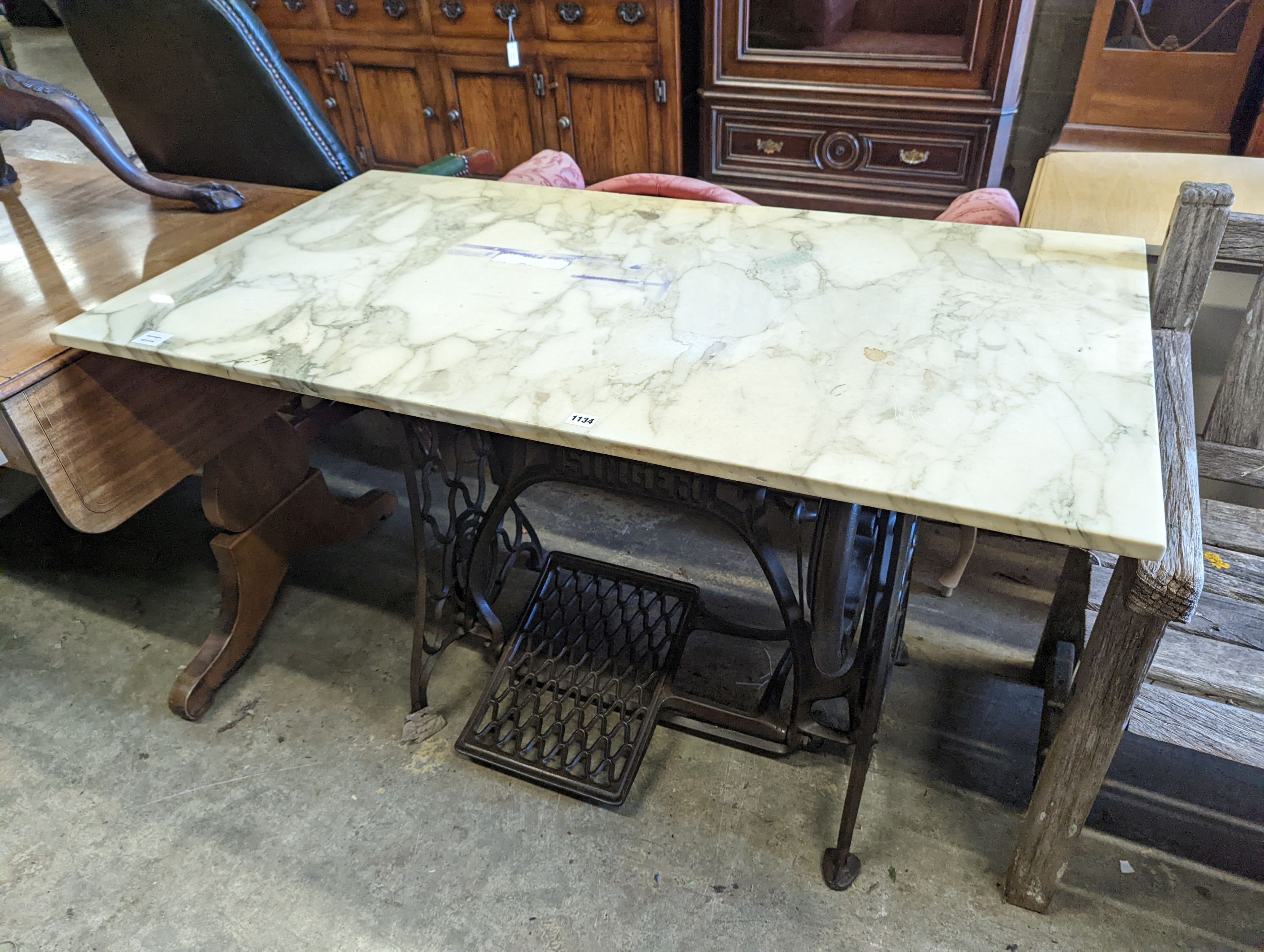 A Singer sewing machine treadle base with later marble top, width 130cm, depth 70cm, height 76cm